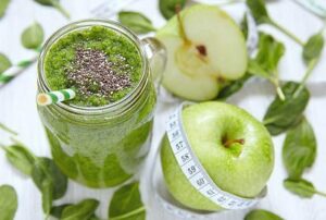 Apple and spinach smoothie in glass on a wooden background